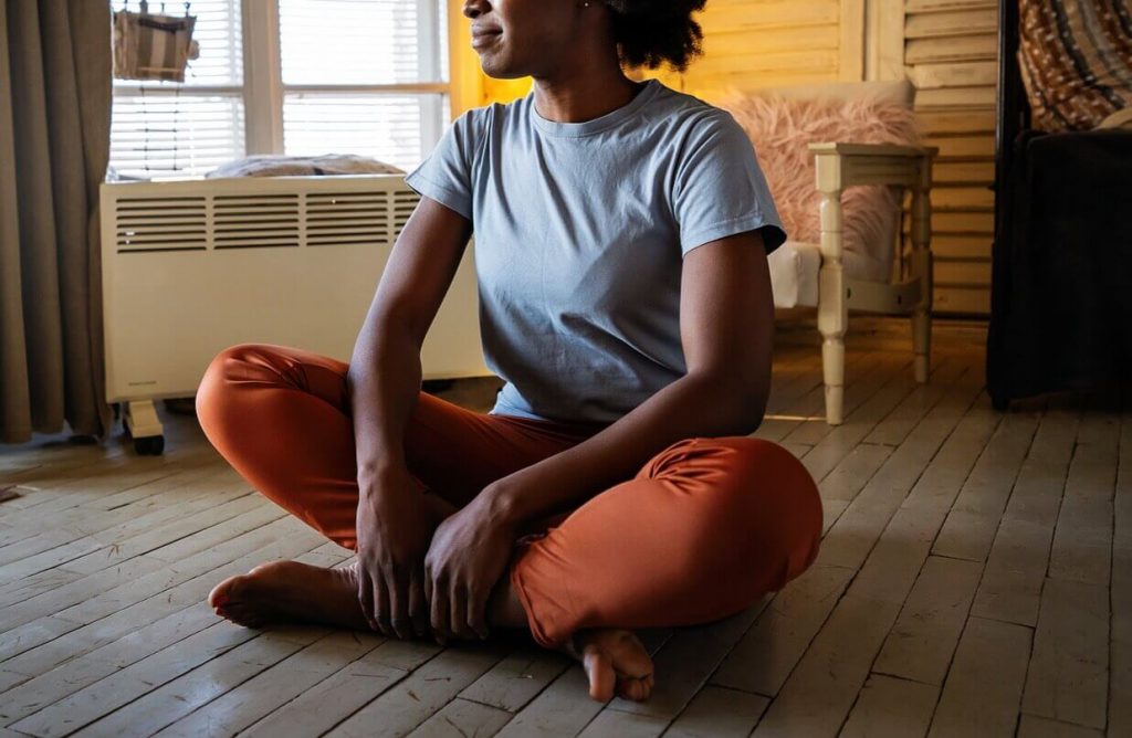 Image of a smiling woman sitting with her legs crossed on a wooden floor. With the help of neurofeedback therapy for ADHD in Englewood, CO you can work to positively manage your ADHD symptoms and take back control.