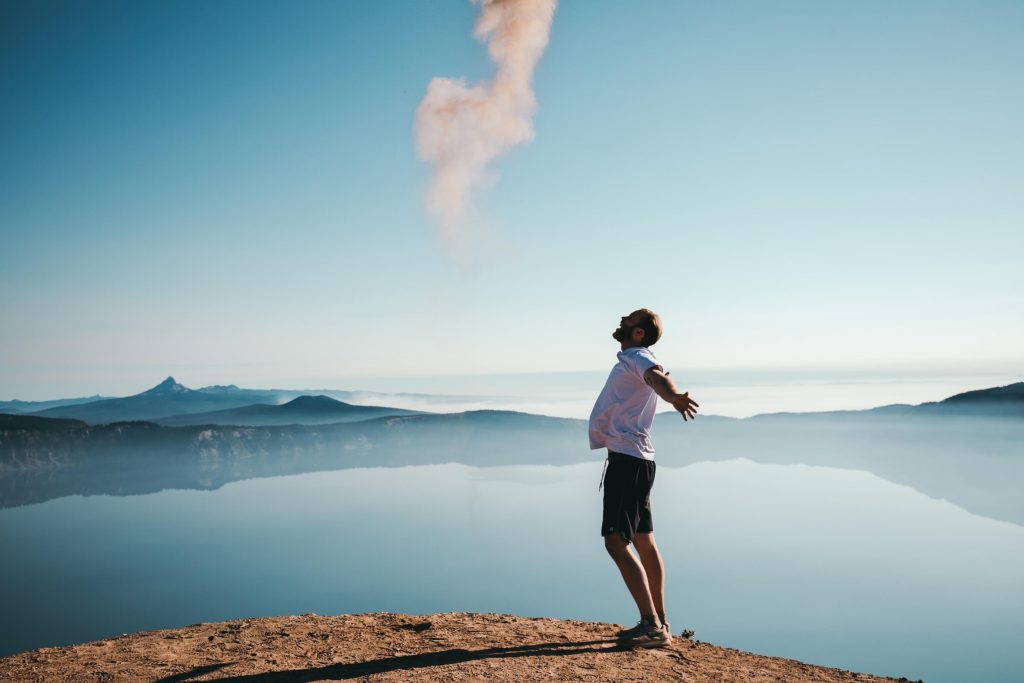 Image of a man standing on top of a mountain smiling with his arms outstretched. If your symptoms of anxiety, ADHD, or Autism are unable to be managed, learn how neurofeedback therapy in Englewood, CO can help.