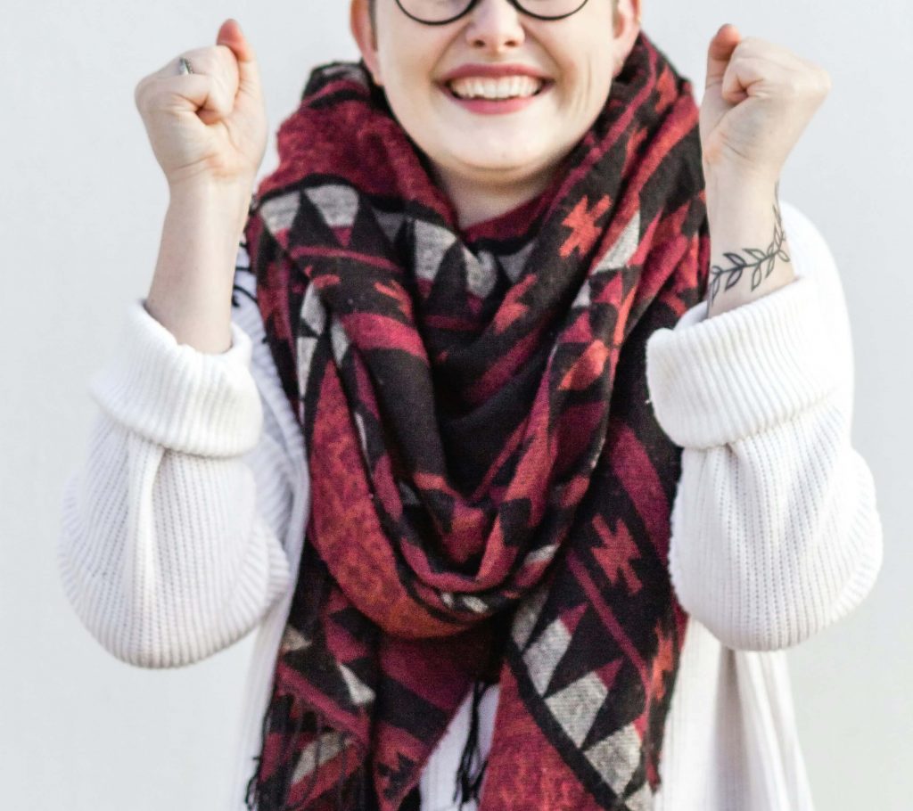 Image of a happy woman smiling and holding her hands up. Do you struggle with anxiety? Learn how neurofeedback therapy in Englewood, CO can help you cope.