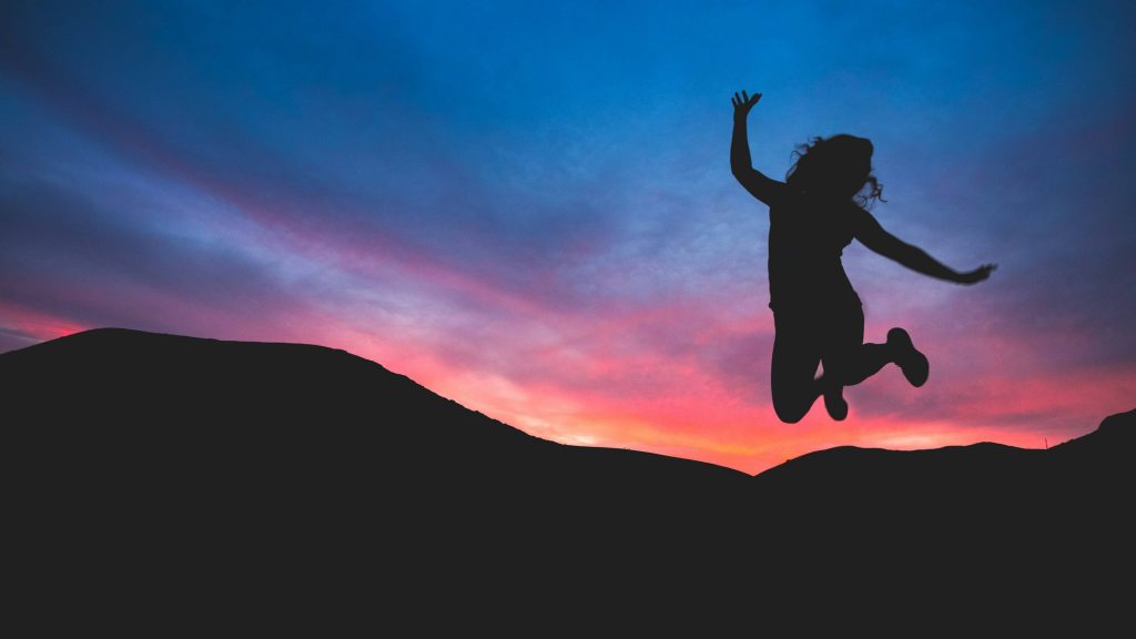 Image of a woman jumping happily in the air during sunrise. Discover how neurofeedback therapy in Denver, CO can help you cope with your anxiety, austism, ADHD, and more.