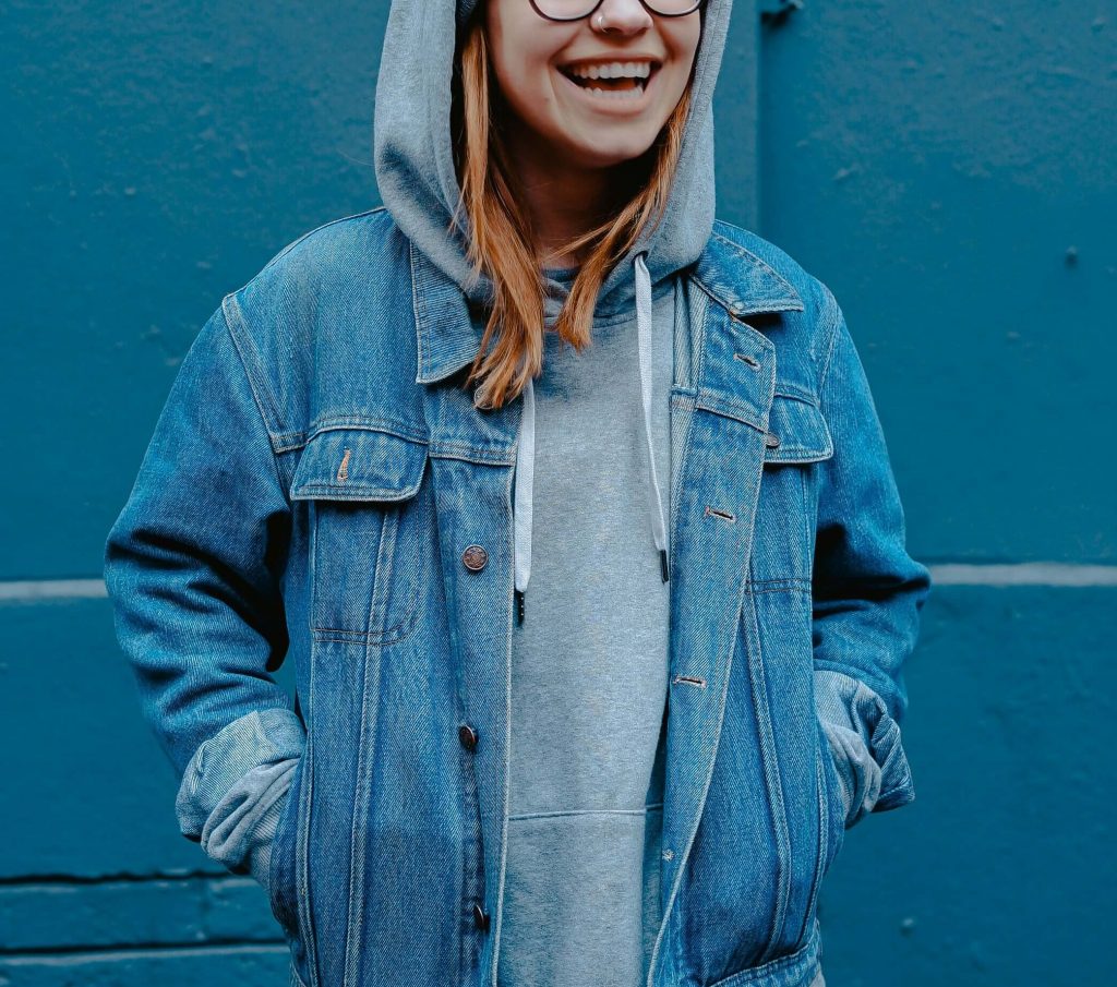 Image of a smiling teen girl wearing a jean jacket and hood. If your teen struggles with anxiety, discover how teen counseling in Littleton, CO can help them!