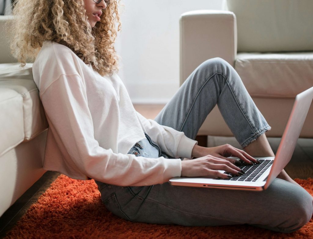 Image of a young woman sitting on the floor using a laptop. Learn how effective EMDR online in Denver, CO can be in healing your anxiety, depression, and more.