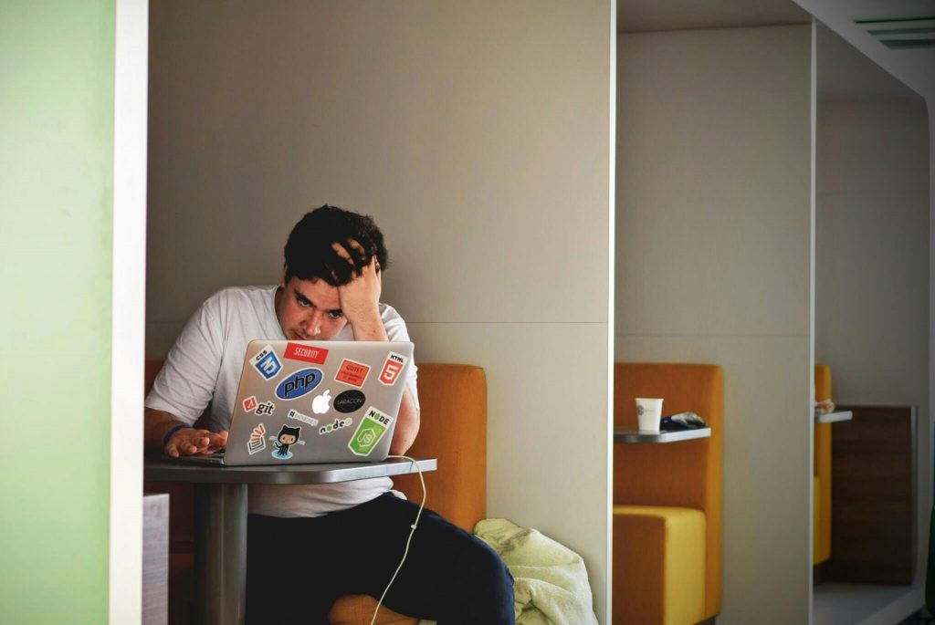 Image of an anxious man running his hand through his hair while working on a laptop. If you are stressed and anxious due to work or school, learn how neurofeedback therapy for anxiety in Denver, CO can help you.
