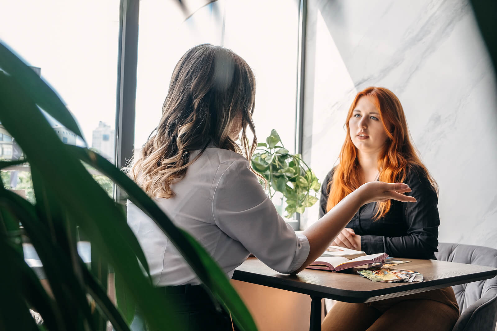 A woman speaks with her therapist in a bright office, representing accessible online therapy in Colorado and highlighting therapists that take UnitedHealthcare near me. 