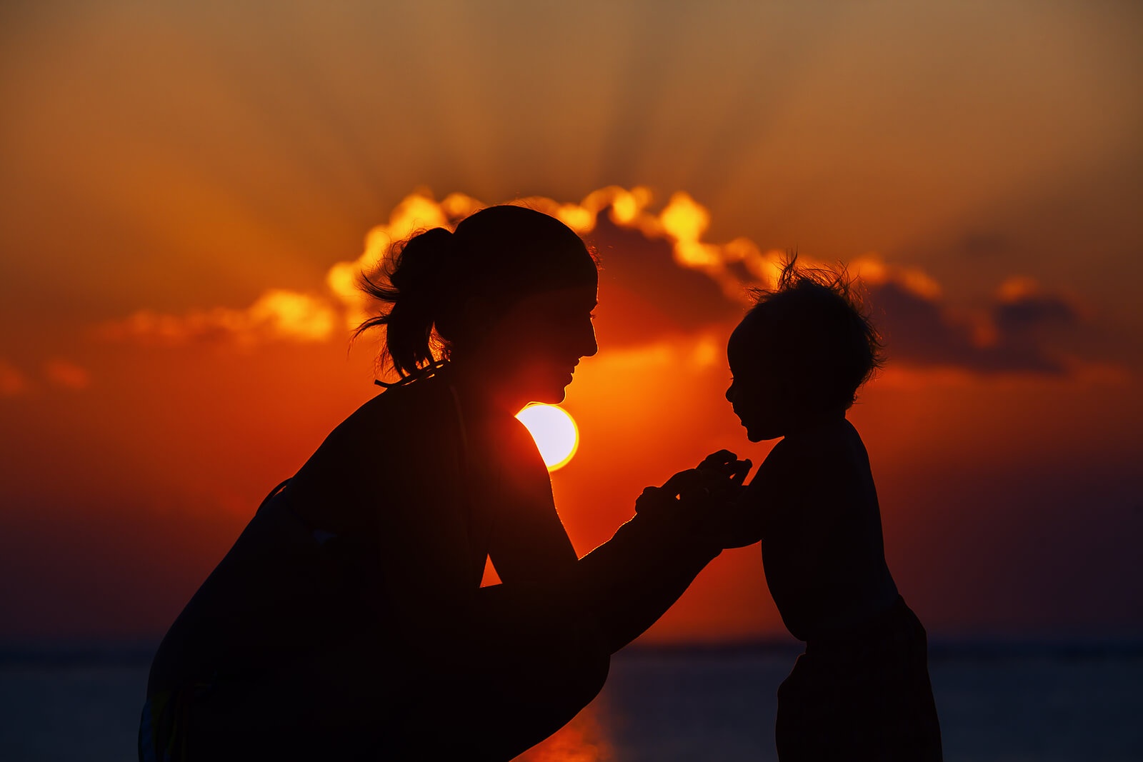A mother and child silhouetted against a sunset, symbolizing the emotional balance found through parenting therapy, support from a maternal mental health therapist, and postpartum anxiety therapy in Greenwood Village, CO. 