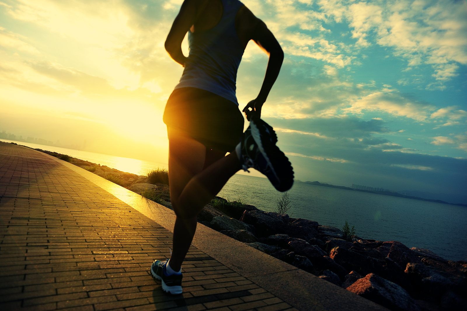 A woman running along a waterfront path at sunrise, symbolizing self-care and stress relief supported by a maternal mental health therapist, therapy for moms, and guidance for managing maternal anxiety. 