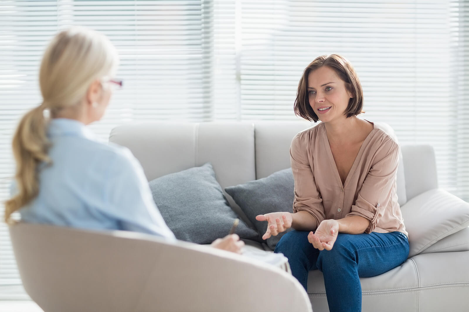 A woman in conversation with a therapist in a bright office, illustrating the benefits of working with a maternal mental health therapist, accessing parenting therapy, and receiving postpartum anxiety therapy in Greenwood Village, CO. 