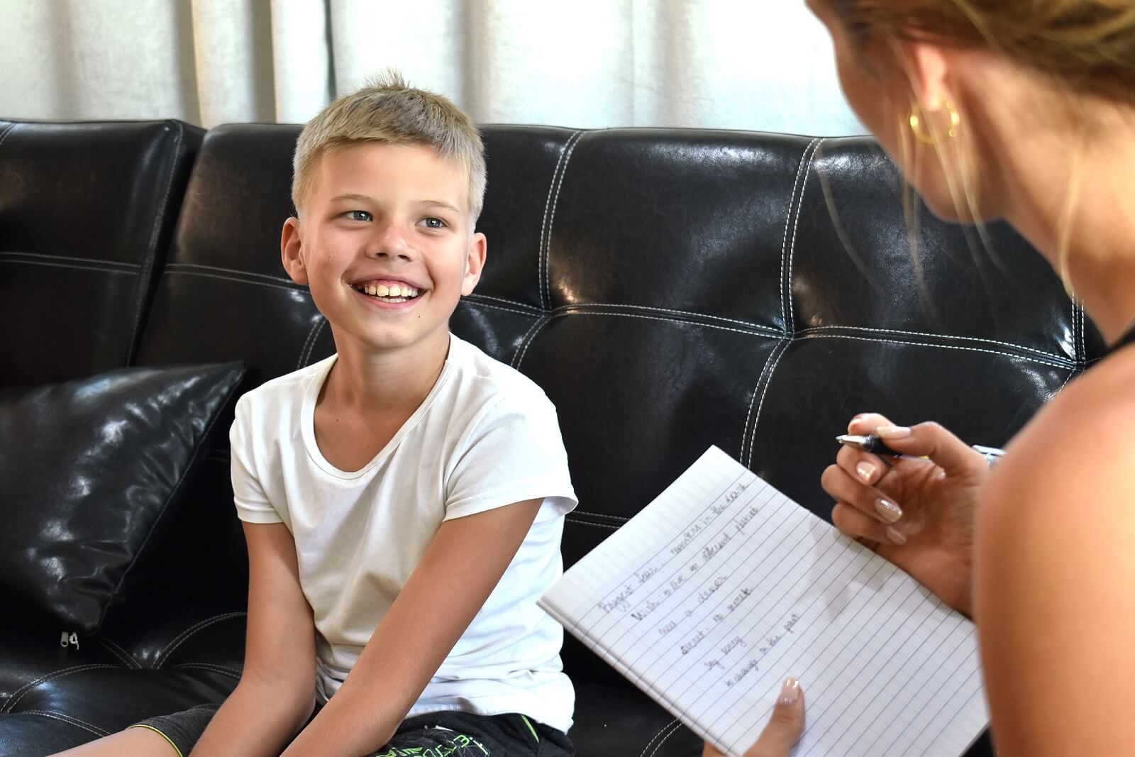 specialist testing child | child therapist in englewood, co | child therapy in littleton, co | learning disability evaluation in denver, co | denver, co | littleton, co | englewood, co | greenwood village, co A young boy smiles warmly during a one on one session with an evaluator, who takes notes on a notepad. This relaxed and engaging dynamic is exactly what families can expect when pursuing a learning disability evaluation in Denver, CO. A skilled child therapist in Englewood, CO works to make children feel safe, comfortable, and at ease throughout the entire testing process.